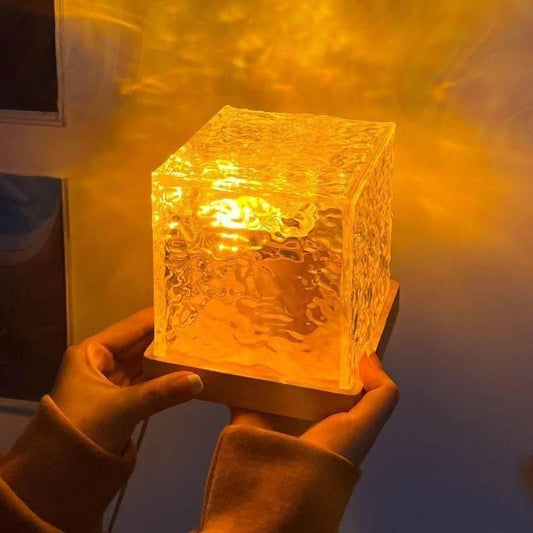 Clear glass cube light held by hands with a warm glow