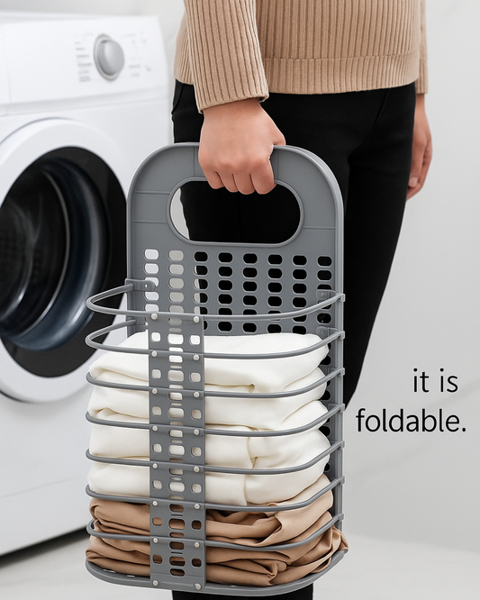 Person holding a gray folding laundry basket filled with clothes in front of a washing machine.