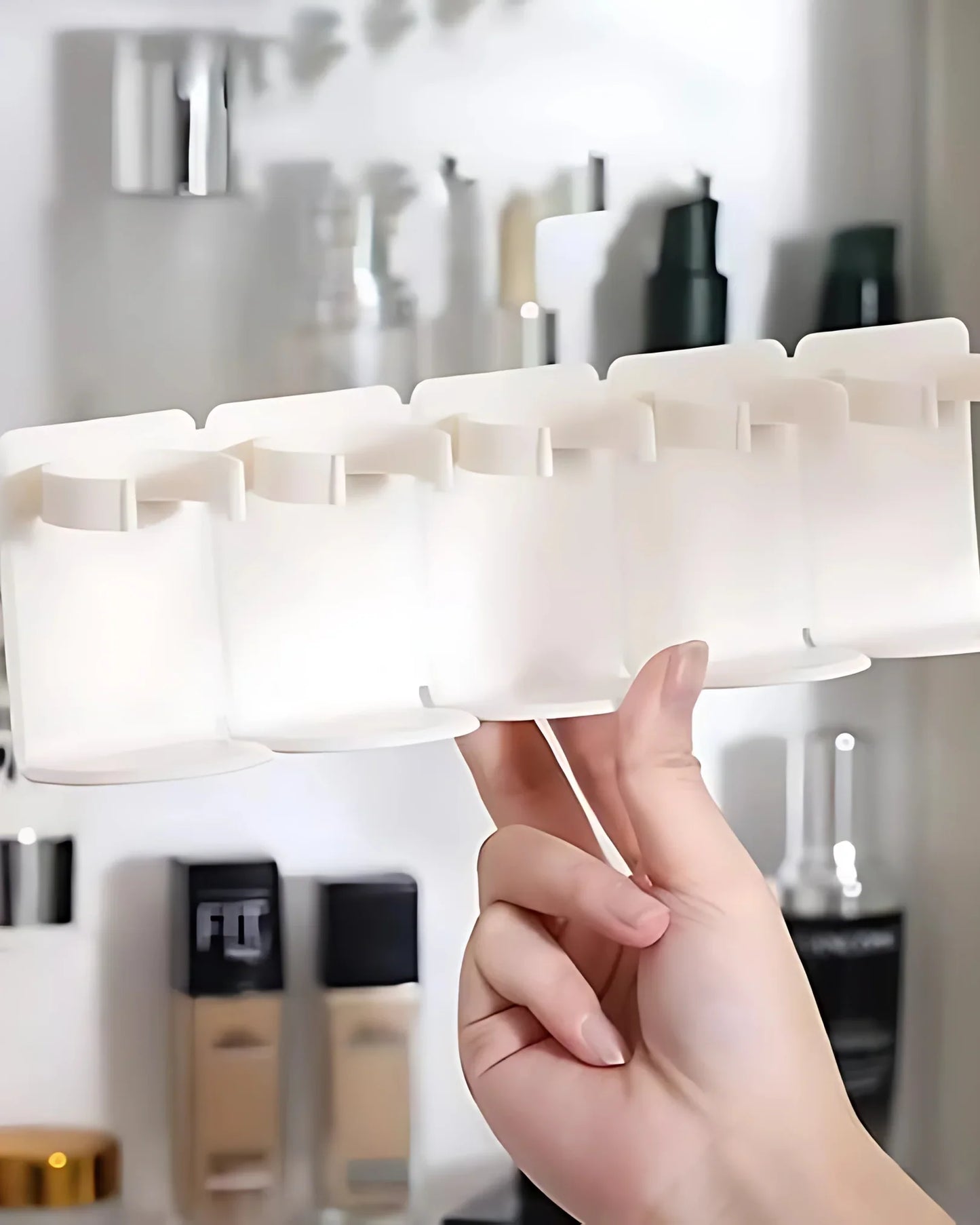 Hand holding a white makeup organizer with cosmetic bottles in the background