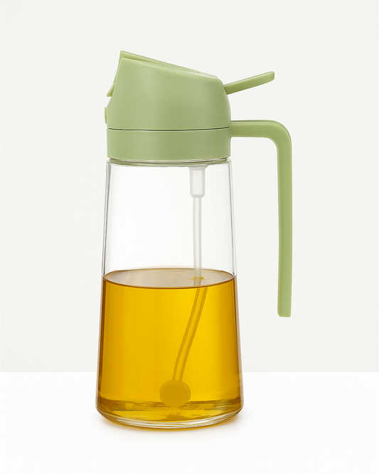 A clear glass oil dispenser with a green lid and spout cap, containing yellow liquid, likely oil.