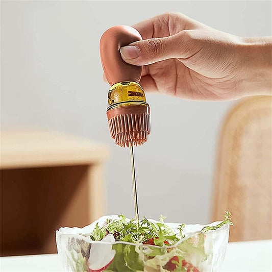 Hand using a small bottle to drizzle oil over a salad.
