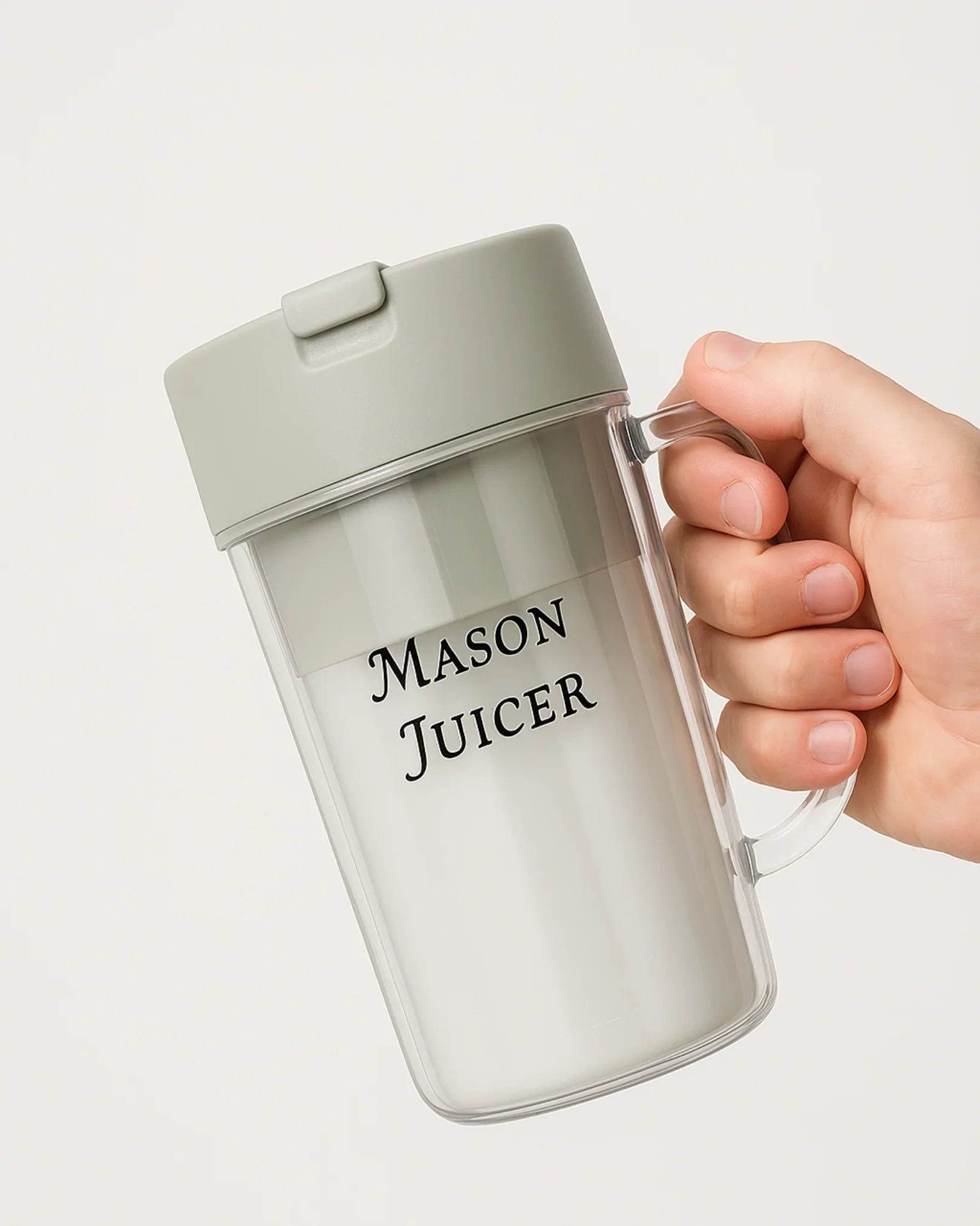 Hand holding a transparent juicer with 'Mason Juicer' branding on a light gray background