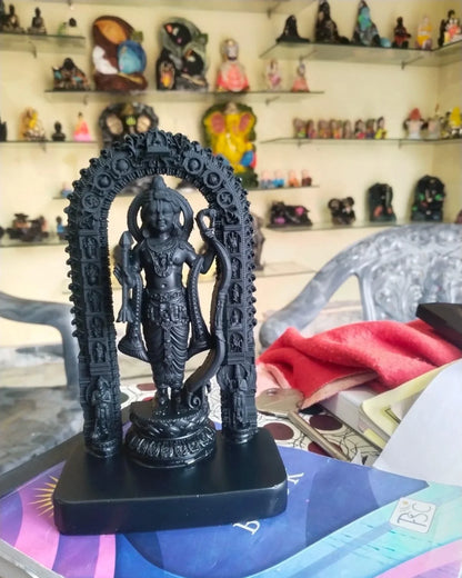Black statue of a deity with an arch in front of a shelf with various small statues.