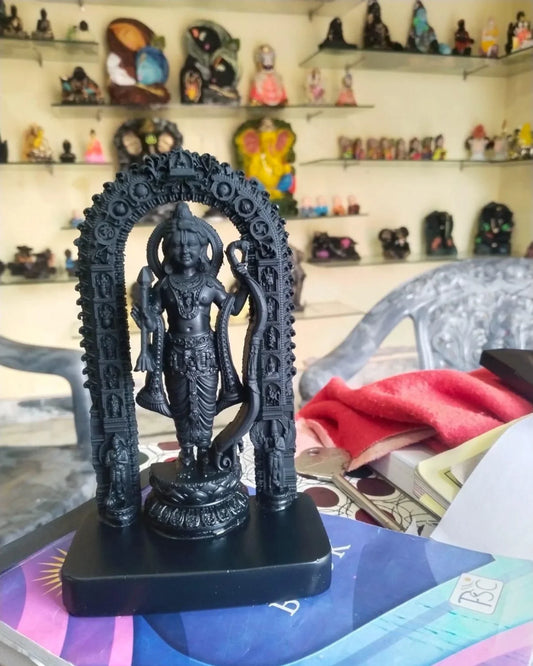Black statue of a deity with an arch in front of a shelf with various small statues.