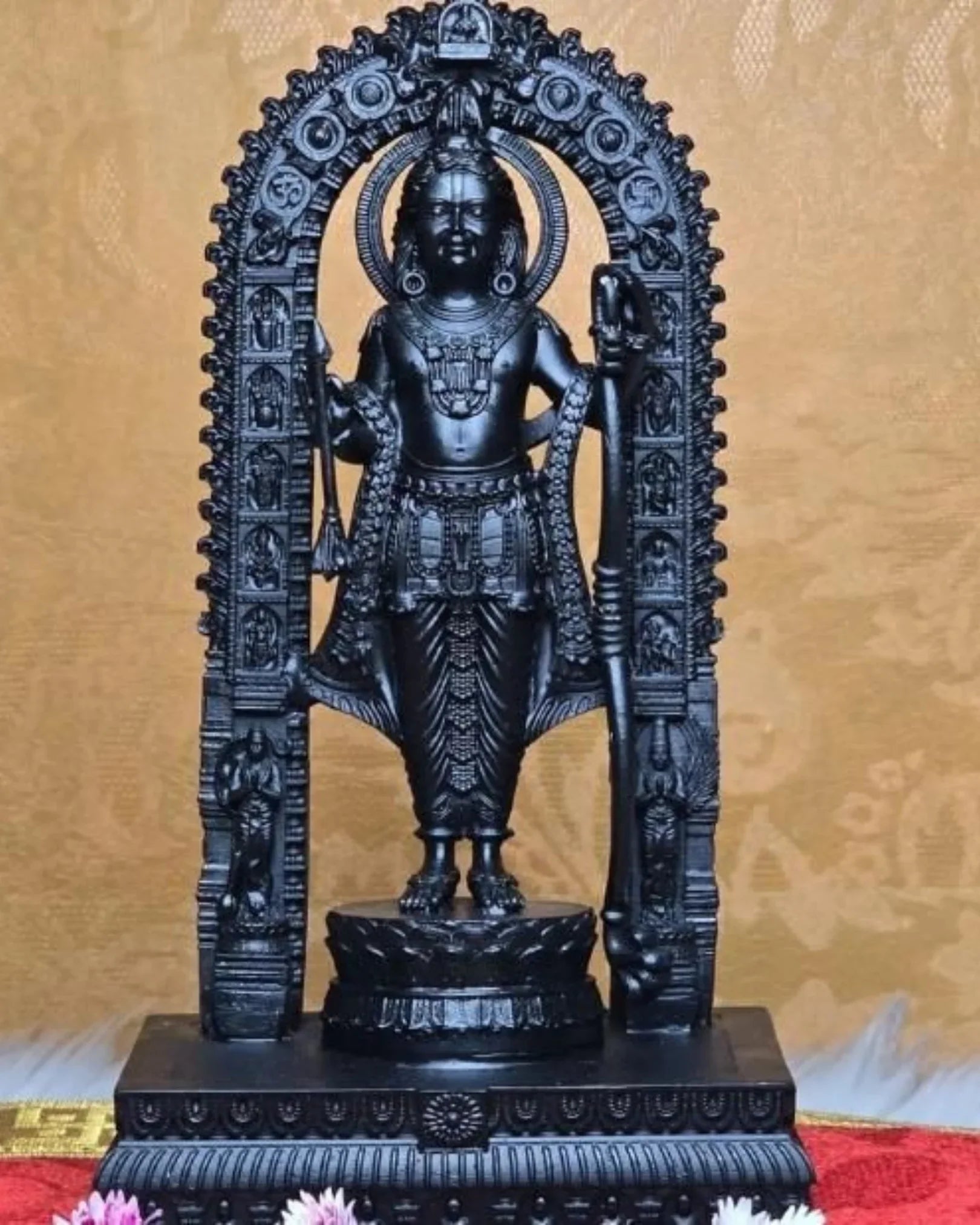 Black stone statue of a deity with intricate carvings on a decorative background