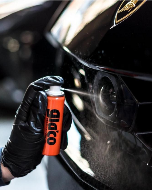 Person cleaning a car window with a Glaco spray bottle.