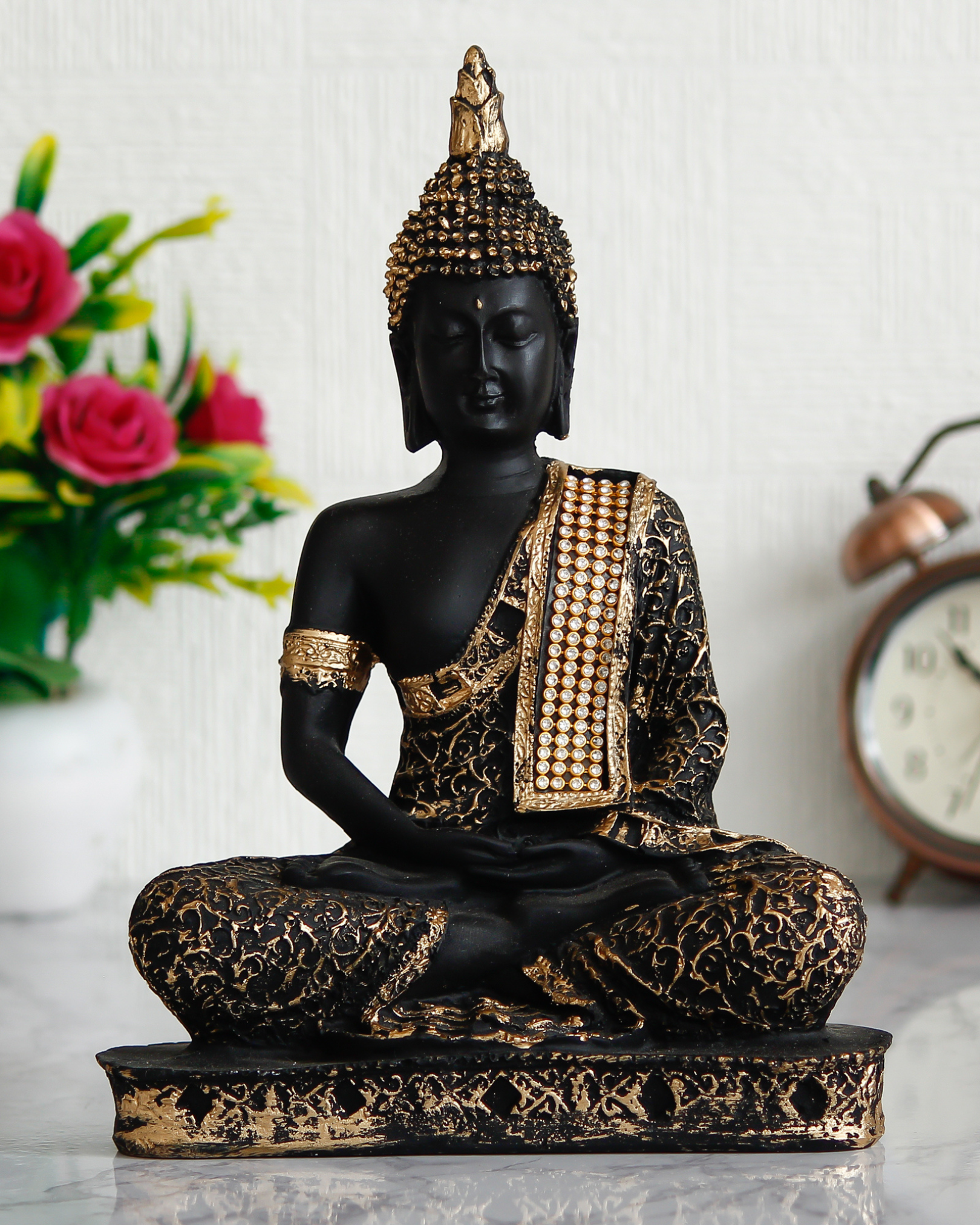 Decorative Buddha statue with black and gold details on a white surface.