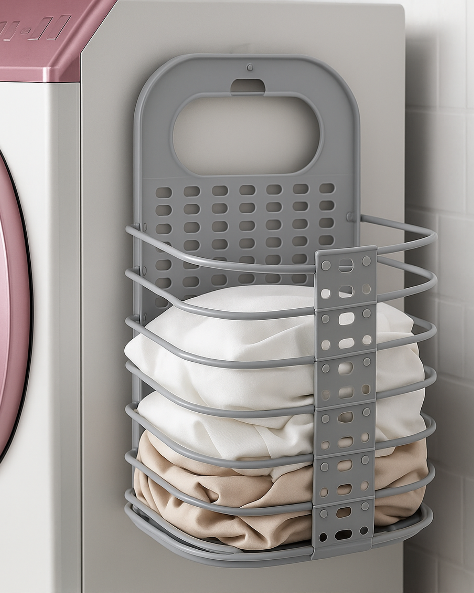 Gray laundry basket with clothes inside attached to a washing machine.