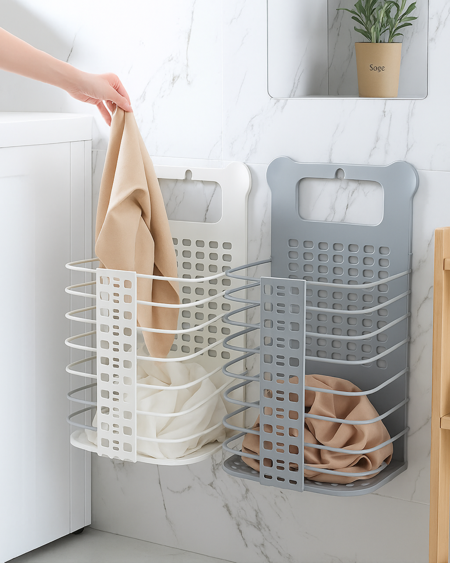 Wall-mounted laundry basket with a hand hanging a towel on a marble wall.