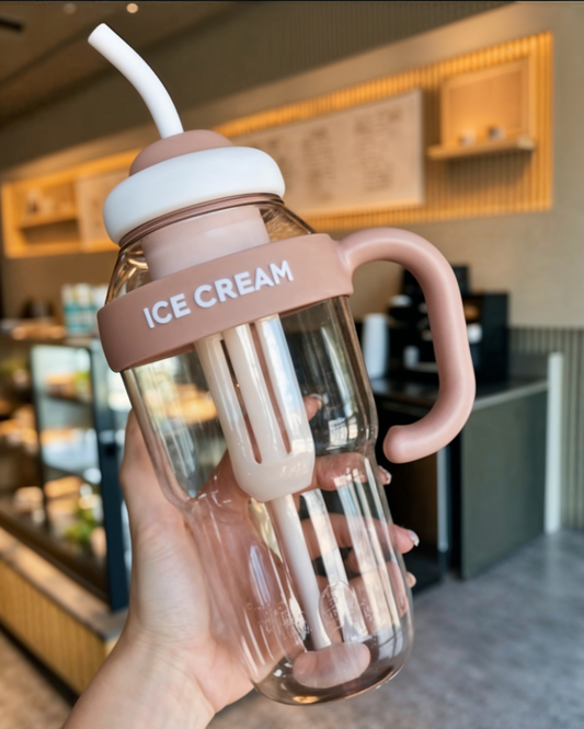 A person holding a large pink water bottle with a handle and straw, labeled 'ICE CREAM'.