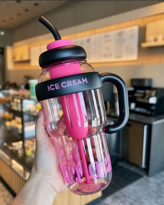 Pink and black ice cream container held in a hand with a cafe background.