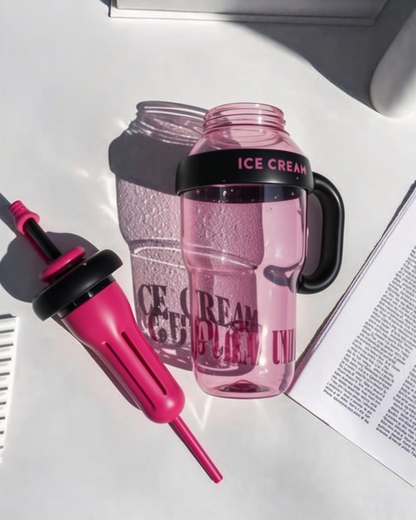 Pink water bottle with black handle and straw on white surface